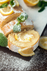 Lemon roll cake decorated with slices of lemon fruit and leaves of mint