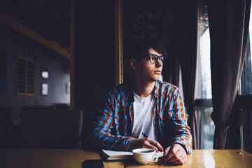 Cheerful student laughing during homework, sitting at coffee table 