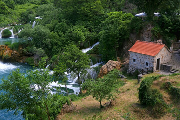 Old traditional watermill on river Krka in National Park Krka, Croatia. Beautiful watrefalls in the background. Krka is popular summer travel destination.