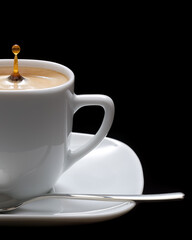a Cup of coffee on a black background with a falling drop