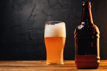 Glass of cold pale beer placed on a rustic wooden table