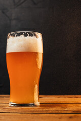 Glass of cold pale beer placed on a rustic wooden table