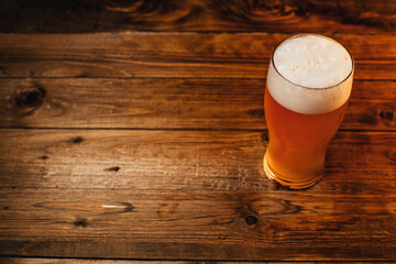 Glass of cold pale beer placed on a rustic wooden table