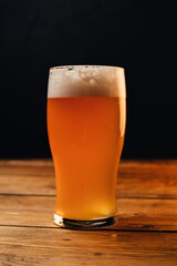 Glass of cold pale beer placed on a rustic wooden table