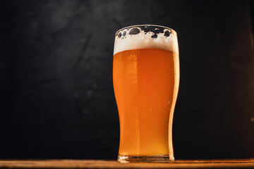 Glass of cold pale beer placed on a rustic wooden table