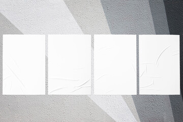 Closeup of geometrical gray painted urban wall texture with four wrinkled glued poster templates....