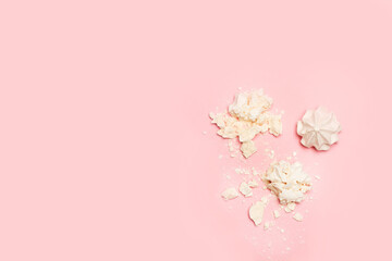 Fototapeta na wymiar Malvaviscos merengue blancos desmenuzado y entero en forma de rosa sobre un fondo rosa liso y aislado. Vista superior. Copy space