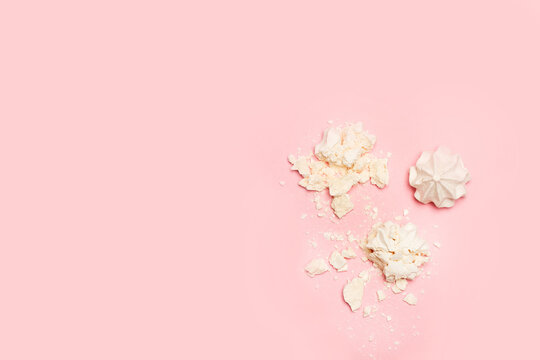Malvaviscos merengue blancos desmenuzado y entero en forma de rosa sobre un fondo rosa liso y aislado. Vista superior. Copy space
