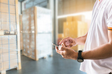 Warehouse cargo courier and transport. Shipper man hand holding smartphone is contact with customers to sending the shipment.