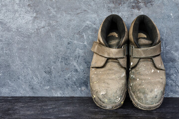 Dirty old shoes on black wooden floors and gray walls.