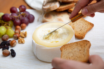 Hand holding toasted bread and taking soft cheese with knife. Traditional rustic breakfast. Studio shot. Selective focus. Side view. Dairy meal and cooking on isolation concept for flyers and banners