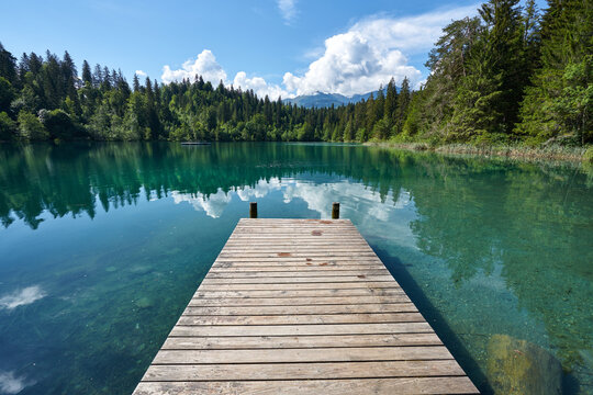 Landscape panorama of Crestasee - Lake Cresta in June, municipalities of Flims and Trin in the Grisons, Switzerland. Wooden dock on the lake.      