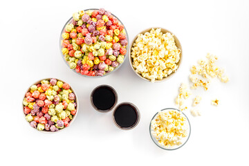 Set of flavored popcorn and soda on white table top-down