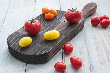 Naklejka na ściany i meble tasty ripe tomatoes on wooden cutting board in rustic style, close-up, no people
