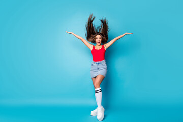 Full size photo of astonished cheerful positive girl impressed by strong spring wind her haircut fly throw hold hand scream wow omg wear singlet legs isolated over blue color background