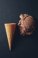 Helado de chocolate con cono de galleta sobre fondo negro.