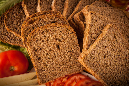 rebanadas de pan de molde integral cerca con decoraci&oacute;n de tomate y fiambre 