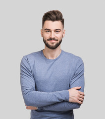 Portrait of handsome smiling young man with folded arms. Serious cheerful men with crossed hands studio shot. Isolated on gray background