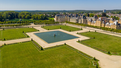 Aerial view of medieval landmark royal hunting castle Fontainbleau near Paris in France and lake with white swans