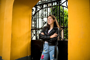 a girl of Eastern appearance poses against a yellow wall