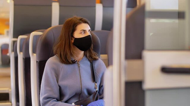 health, safety and pandemic concept - young woman in protective black face mask in electric train