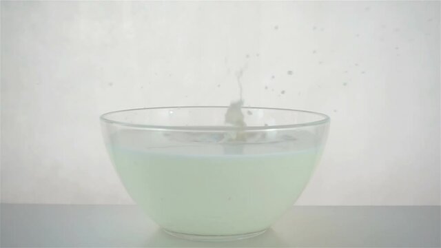 Red strawberry falls in slow motion into a bowl of milk. Splashing milk on white background