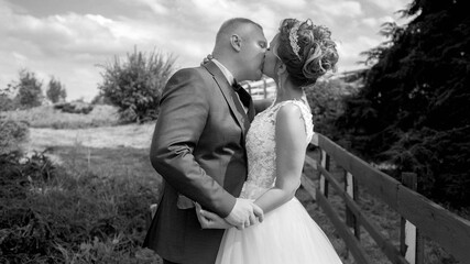 Fototapeta na wymiar Black and white portrait of happy newly married couple kissing at countryside