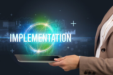 Close-up of a touchscreen with IMPLEMENTATION inscription, new technology concept