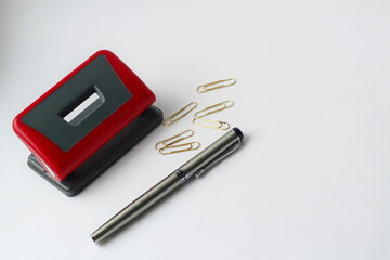 stationery, hole punch, paper clips and pen for writing on a white background