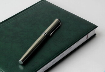 green notebook with pen on a white background