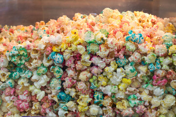 Close-up texture of multi-colored popcorn in a glass movie theater container. Popcorn with a variety of colors and flavors.