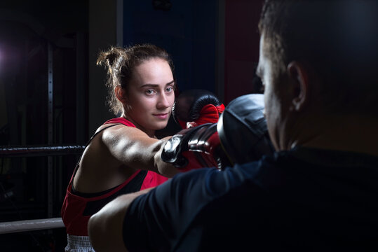Portrait of a boxing trainer guy training a young athlete training her in martial arts. In a boxing club. Girls learn self-defense, martial art.