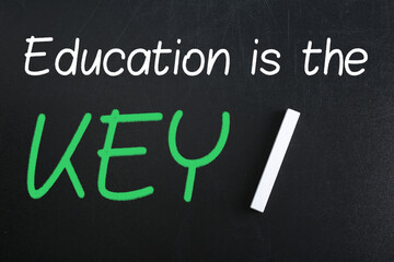 Piece of white chalk and phrase Education is the KEY on blackboard, flat lay. Adult learning