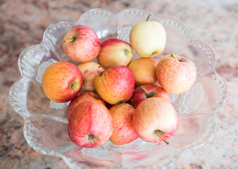 Beautiful fresh & organic colorful apples picked from the garden in a salad bowl on a marble table. Top view close up.