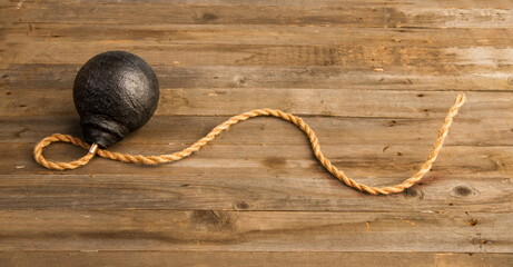 classic round black antique bomb with a long non-burning rope wick on a rough wooden background