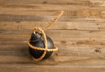classic round black antique bomb with a long non-burning rope wick on a rough wooden background