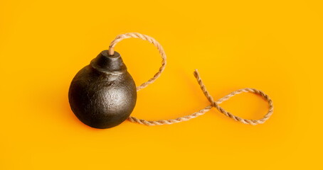 classic round black antique bomb with a long non-burning rope wick on a pink background