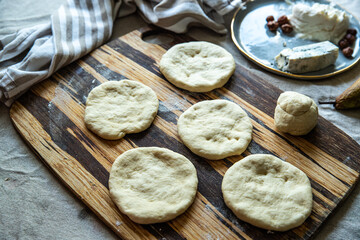 Step by step process of making homemade flatbreads with pear, ricotta, gorgonzola and hazelnuts. Dough ball and flat breads on wooden board.