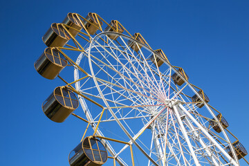Ferris wheel against the blue sky in an amusement park.