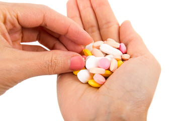 Hand with handful of scattered medicines, pills and tablets on white background.