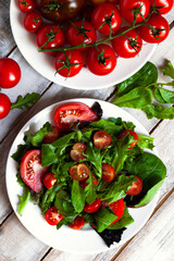 Healthy and light summer lunch: fresh green salad with ripe red tomatoes. Low calories delicious meal, vegan and vegetarian diet. Everyday source of vitamin. Flat lay top view, wooden background