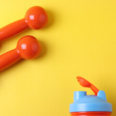 orange small dumb bells on the yellow background, representing healthy lifestyle or sport motivation concept
