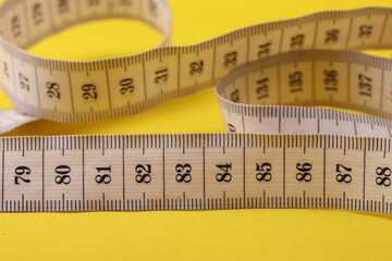white centimeter ruler on a yellow background representing tracking the length or diet concept