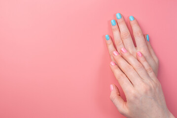 Women's hands with a bright summer manicure on a pink background. Trendy glamorous nails in fun colors. Copy space