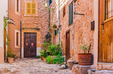 Fototapeta na wymiar Beautiful view of a narrow alley with historic traditional mediterranean houses in an old town in Europe, Spain, Mallorca