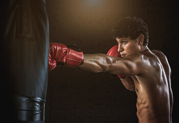 Fototapeta na wymiar Muscular man doing exercise by boxing in gym