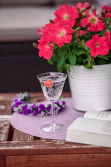 Beautiful composition with glass of water with old book and flower  on table close up