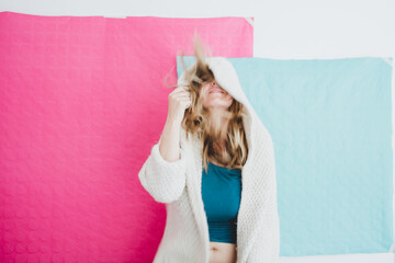 Happy girl dancing in a white hooded jacket. Pink and turquoise paper background