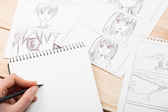 Artist drawing an anime comic book in a studio. Wooden desk, natural light. Creativity and inspiration concept.