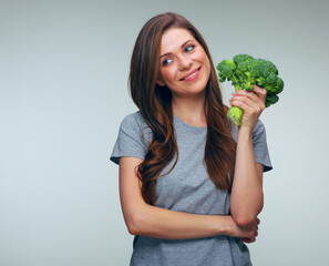 Smiling woman holding big green broccoli looking away.